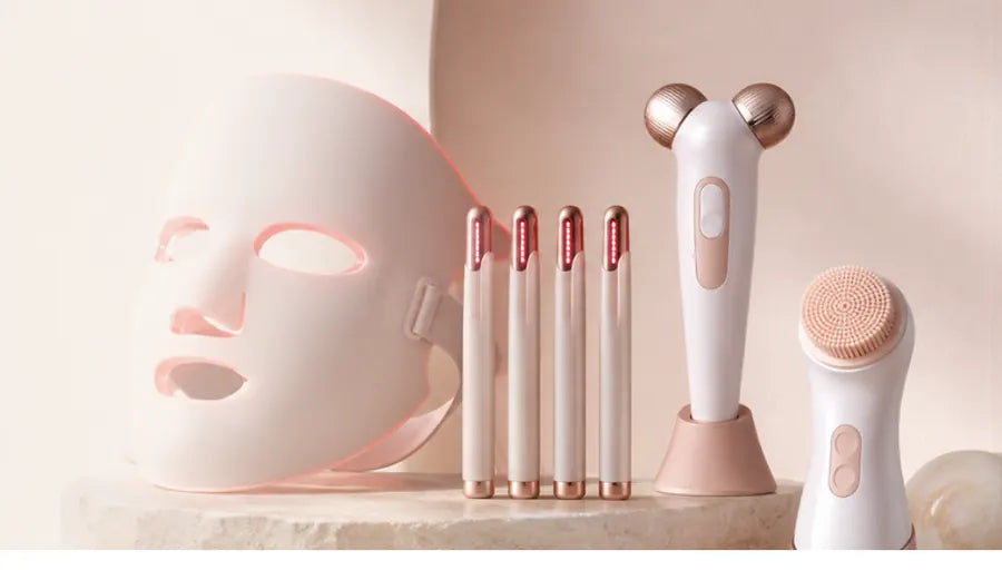 Lumeque red light therapy face mask, LED pen, facial massager and electric scrubber grouped together on a stone surface